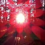 Album cover for Empros by Russian Circles, showing a blurry image of a person walking in the woods, with the album title and band name in the top center